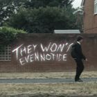 teen walking past wall with text saying "they won't even notice"