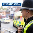 Investigation graphic showing officer talking into radio on street with ambulance in background