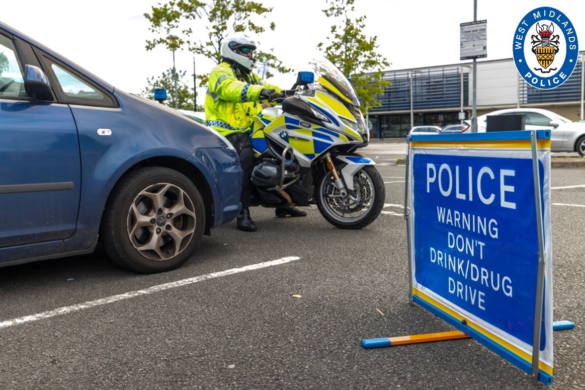 Police motorbike alongside a car and a police sign warning against not drink driving 