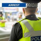 Arrest graphic showing back of police officer and office in background talking to a man