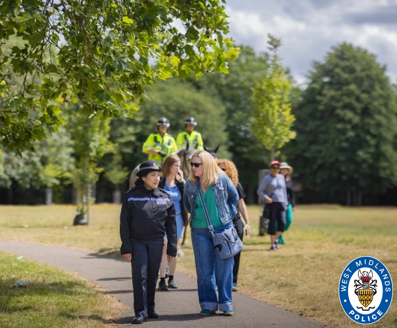 Officers on patrol with mounted unit and members of the public in a park