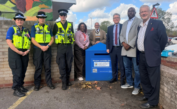 officers and commissioner standing around new weapon surrender bin