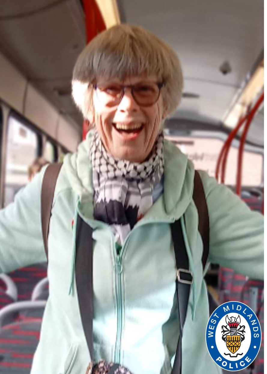 CCTV image of woman with short grey hair, wearing a scarf and mint green coat stood on a bus