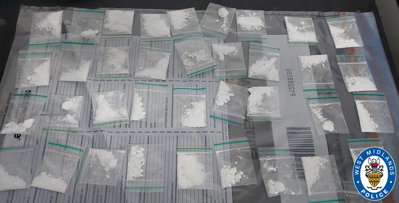 Image of suspected drugs inside clear bags on table on top of evidence bags 
