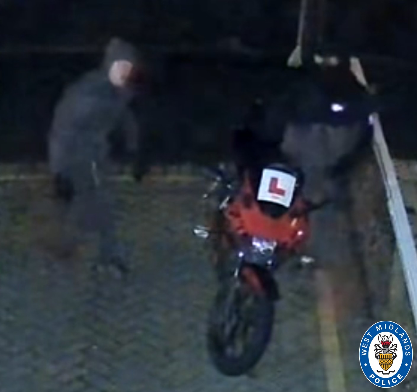 CCTV image of two men stood next to motorbike